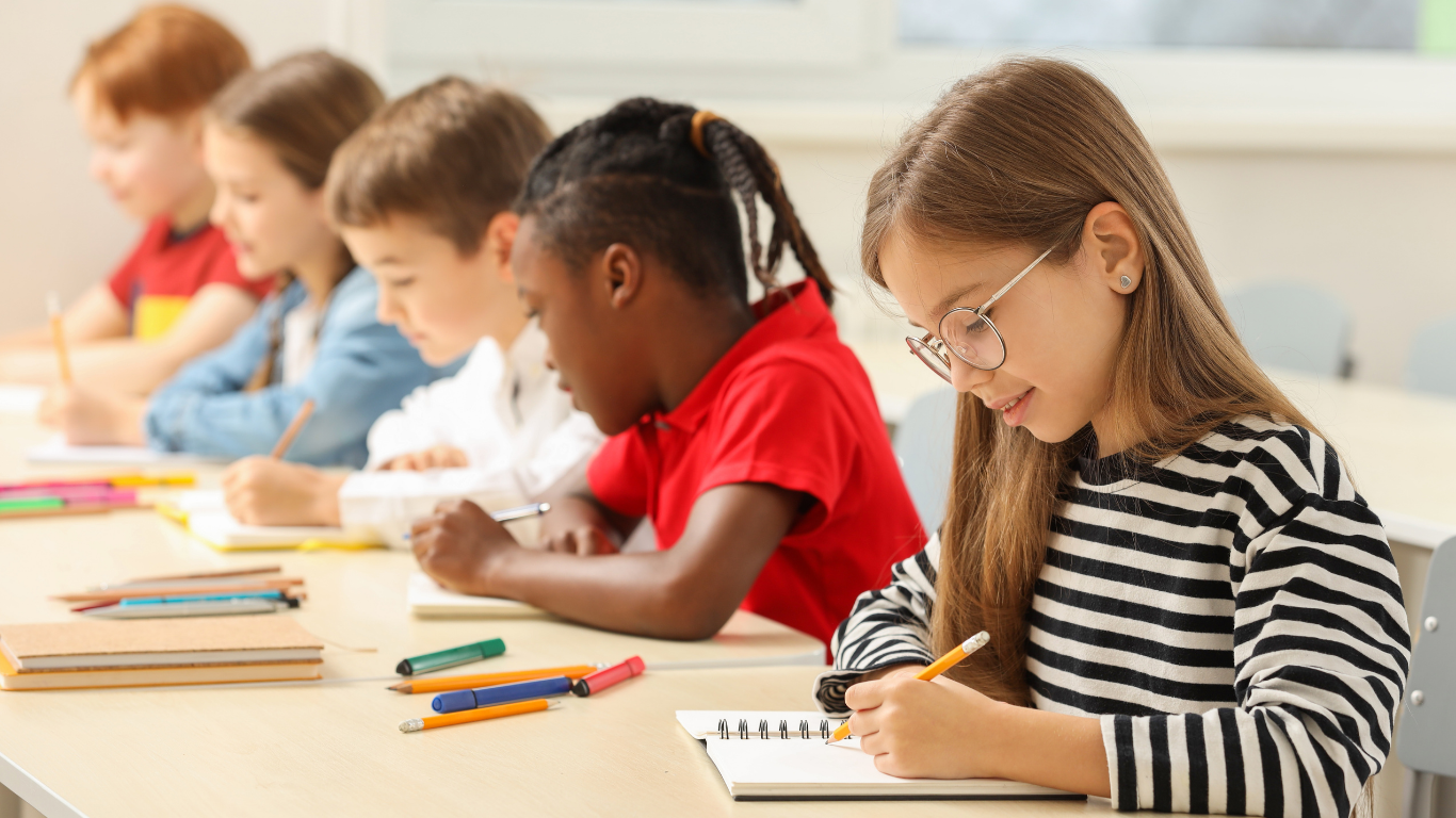 Estudiantes escribiendo y aprendiendo juntos en una sala de clases
